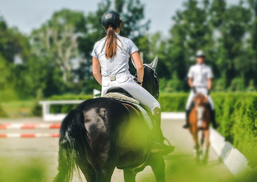 Horse and rider in uniform performing jump at show jumping competition. Equestrian sport background. Selective focus.